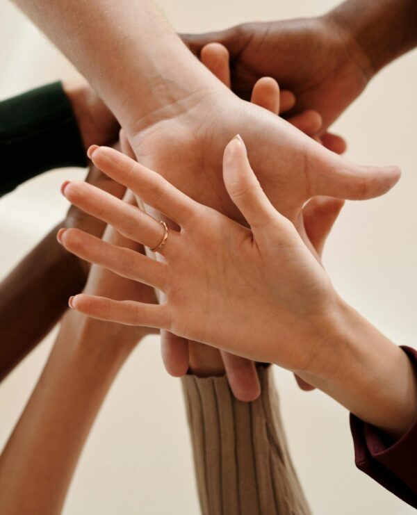 A close-up of diverse hands joined together symbolizing teamwork, cooperation, and unity indoors.